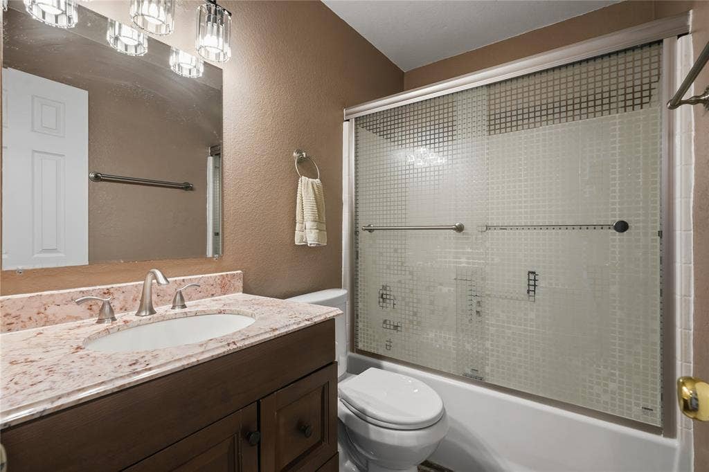 1125 Bayfield Drive, Denton, TX 76209 Brown wood-finish vanity with an undermount sink, a light-colored stone countertop, and a brushed nickel faucet