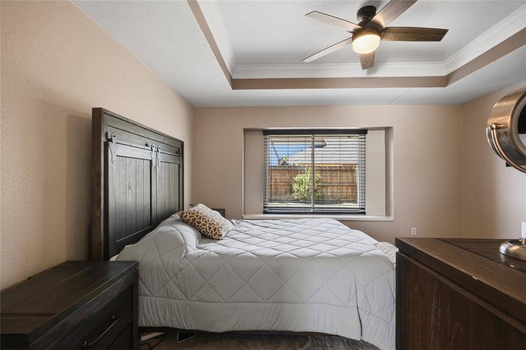 1125 Bayfield Drive, Denton, TX 76209 Tray ceiling with crown molding, ceiling fan with integrated lighting, window with blinds, and wood-finish flooring