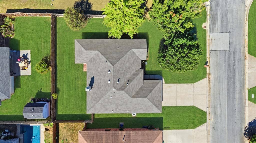 1125 Bayfield Drive, Denton, TX 76209 Gabled roofline, concrete driveway, front yard with mature trees, fenced backyard with manicured lawn, and a storage shed
