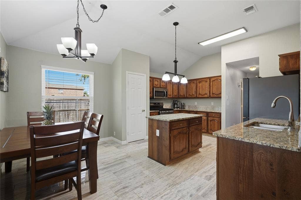 1125 Bayfield Drive, Denton, TX 76209 Vaulted ceiling, recessed lighting, wood-finish cabinetry, granite countertops, and tile flooring