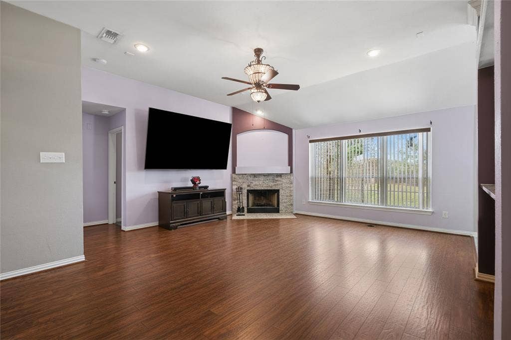 1125 Bayfield Drive, Denton, TX 76209 Wood-finish flooring throughout, vaulted ceiling, recessed lighting, ceiling fan with light fixture, and stone-faced fireplace