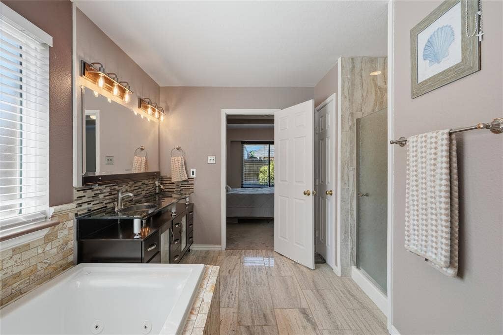 1125 Bayfield Drive, Denton, TX 76209 Spacious bathroom featuring a soaking tub, dual vanity with undermount sinks, and a glass-enclosed shower