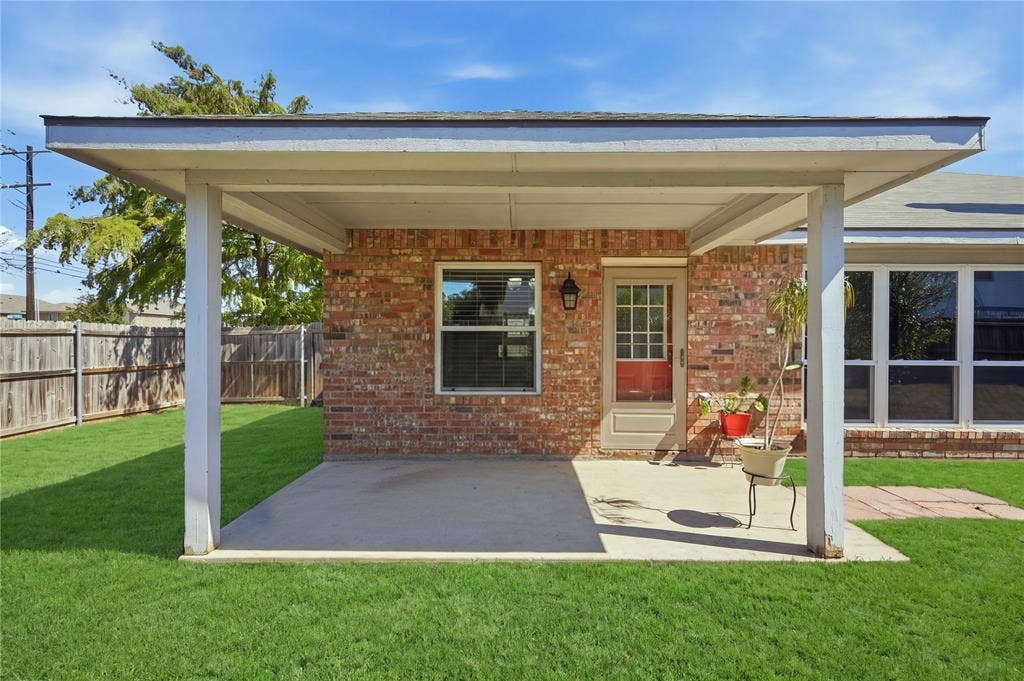 1125 Bayfield Drive, Denton, TX 76209 Expansive backyard featuring a covered patio, brick exterior, wood fence, and abundant natural lighting