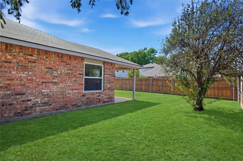 1125 Bayfield Drive, Denton, TX 76209 Expansive backyard with a manicured lawn, brick exterior, and a privacy fence