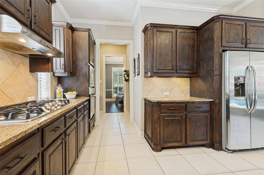1227 Comanche Drive, Allen, TX 75013 Spacious kitchen featuring dark wood cabinetry, granite countertops, stainless steel appliances, and tile flooring