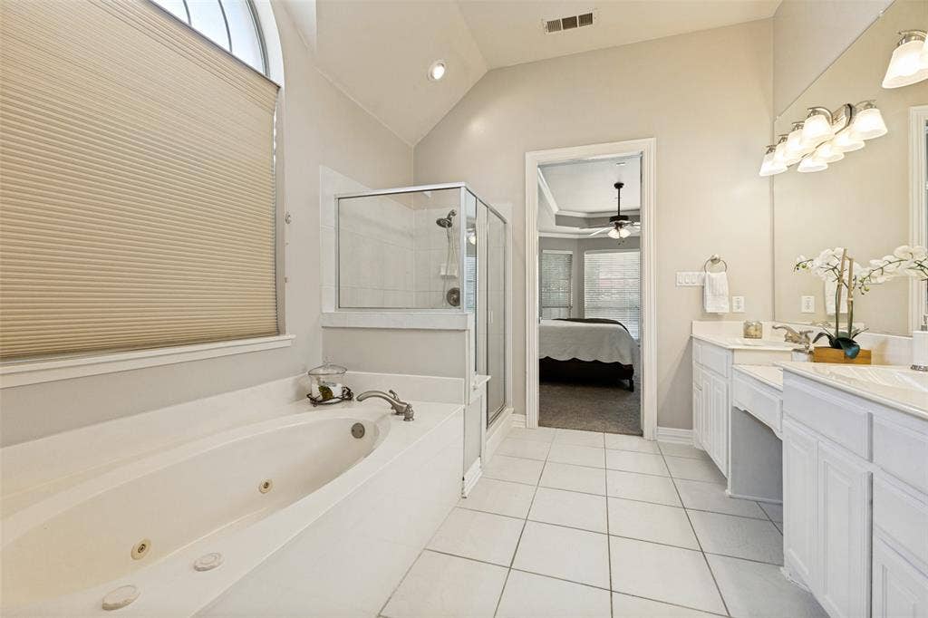1227 Comanche Drive, Allen, TX 75013 White tile flooring, dual vanities with integrated sinks, a built-in jetted tub, a glass-enclosed shower, and a vaulted ceiling