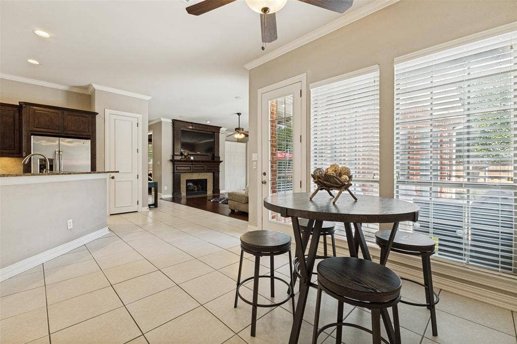 1227 Comanche Drive, Allen, TX 75013 Spacious kitchen and dining area featuring tile flooring, stainless steel refrigerator, dark wood cabinetry, and ample natural light from multiple windows