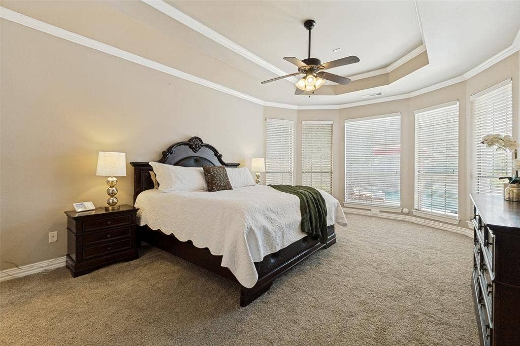 1227 Comanche Drive, Allen, TX 75013 Carpeted room featuring a ceiling fan, tray ceiling, and a bay window with multiple windows