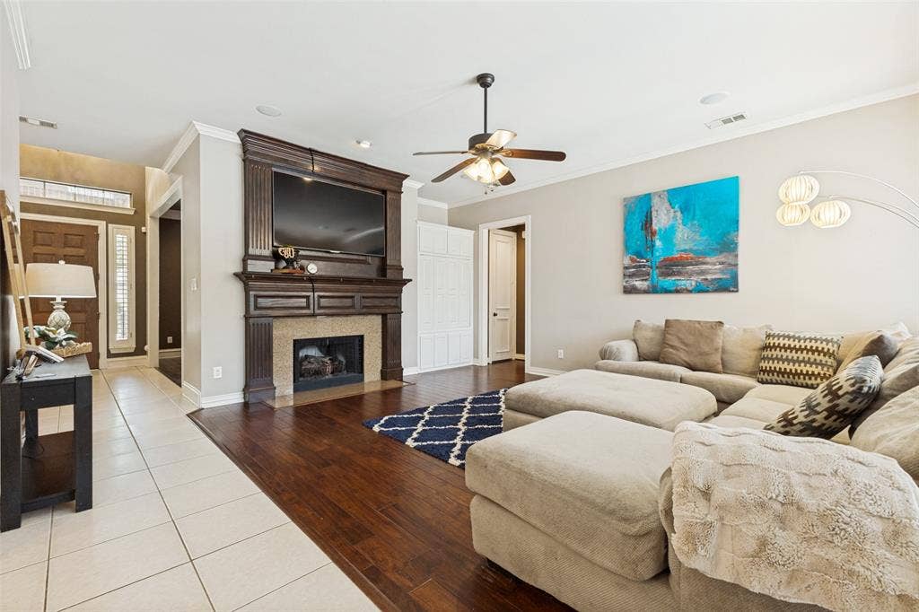 1227 Comanche Drive, Allen, TX 75013 Living area featuring wood-finish flooring, a detailed fireplace with a stone surround and dark wood mantel, and a ceiling fan