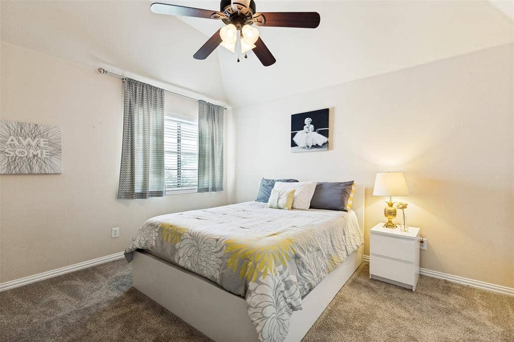 1227 Comanche Drive, Allen, TX 75013 Carpeted room featuring a vaulted ceiling with a ceiling fan, window with blinds, and white baseboards