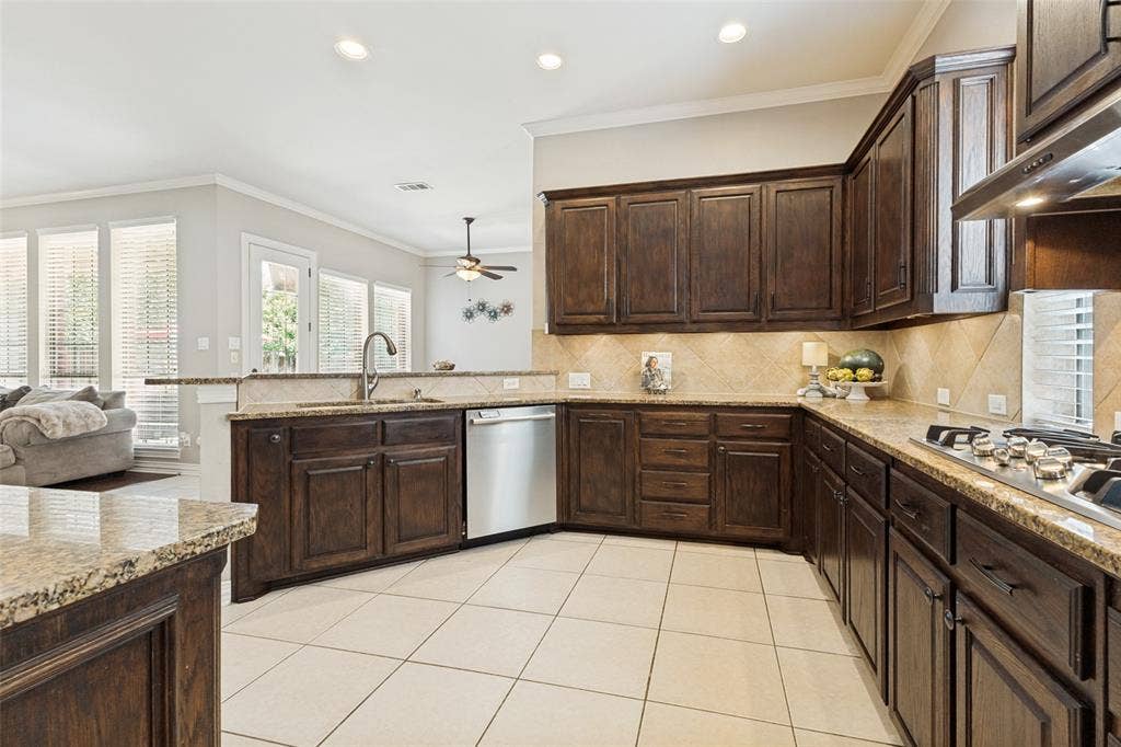 1227 Comanche Drive, Allen, TX 75013 Spacious kitchen featuring dark wood cabinetry, light-toned countertops, and a tile backsplash