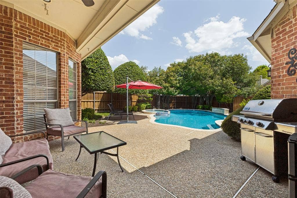 1227 Comanche Drive, Allen, TX 75013 Expansive covered patio featuring an exposed aggregate finish, brick exterior, and a ceiling fan