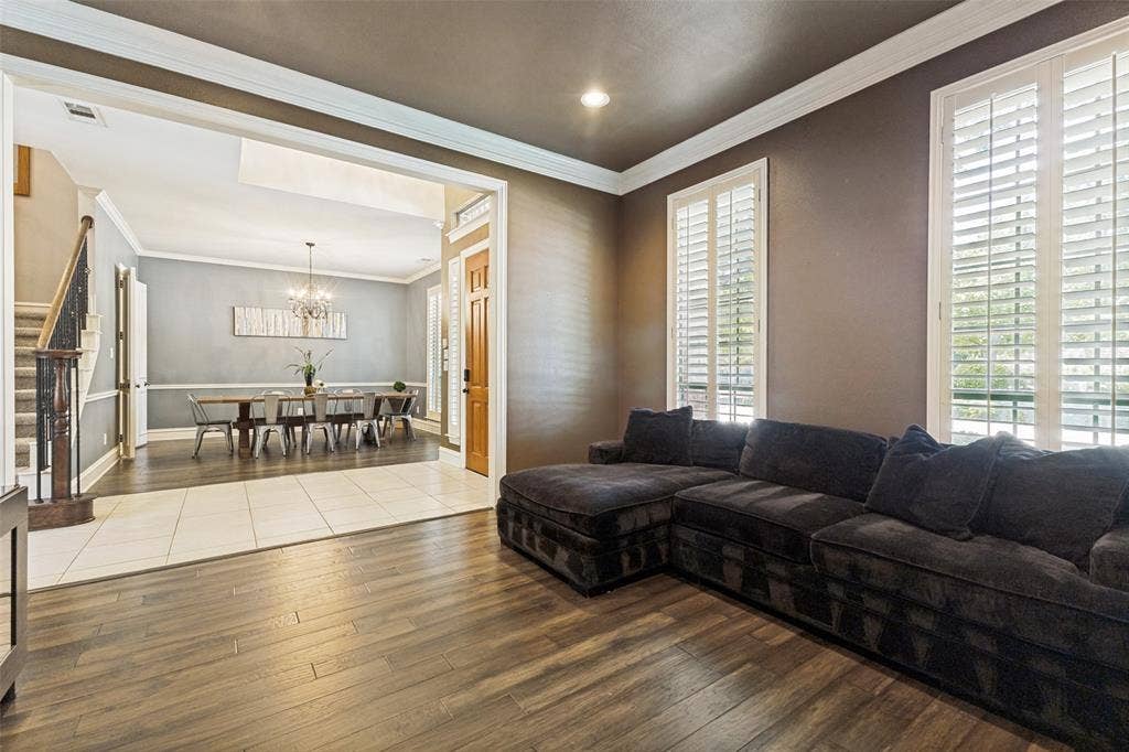 1227 Comanche Drive, Allen, TX 75013 Living area featuring wood-finish flooring, crown molding, and two windows with white plantation shutters