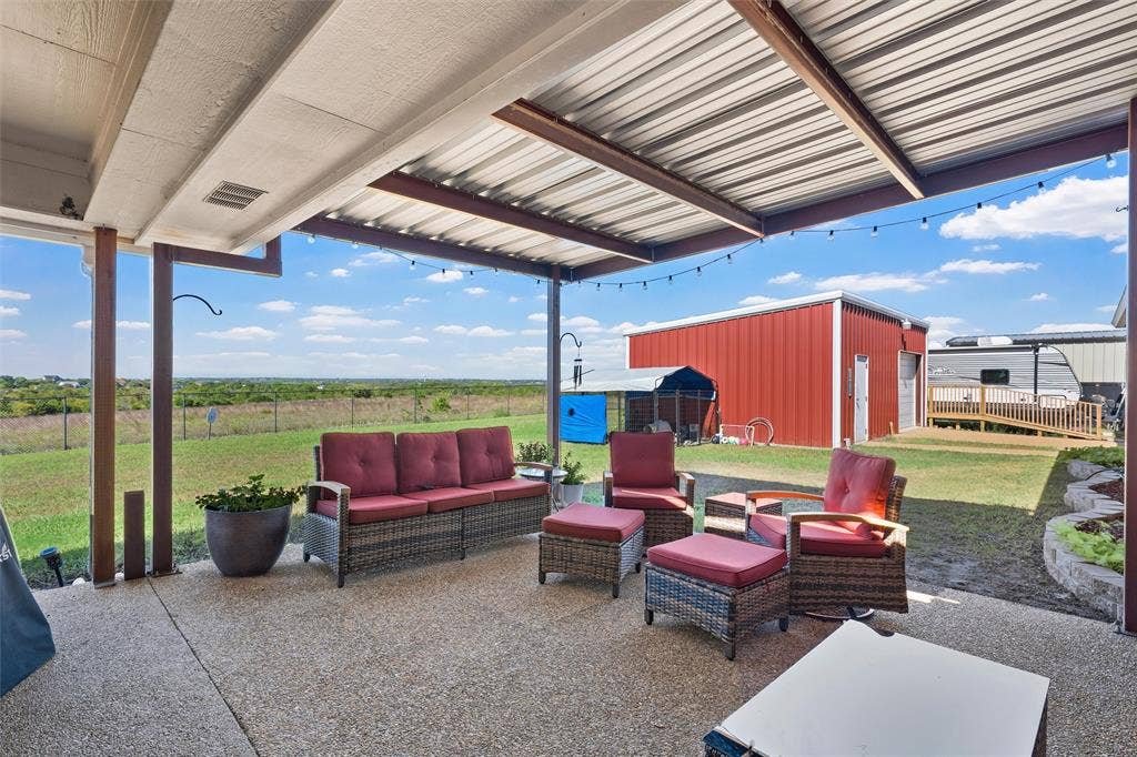 Covered patio featuring a durable metal roof, exposed aggregate concrete flooring, and an expansive open landscape
