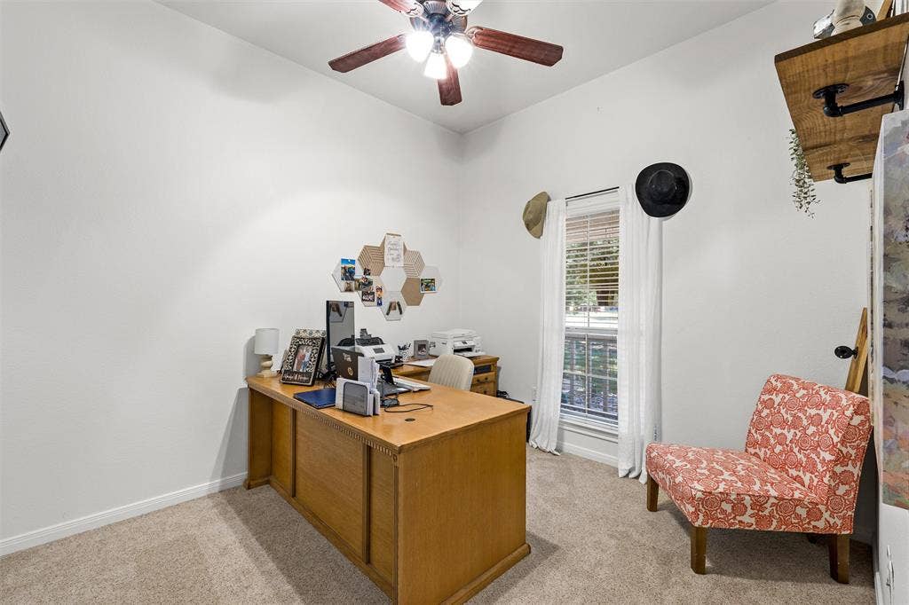 Carpeted room with a ceiling fan, a window with blinds and drapes, and a built-in wall shelf