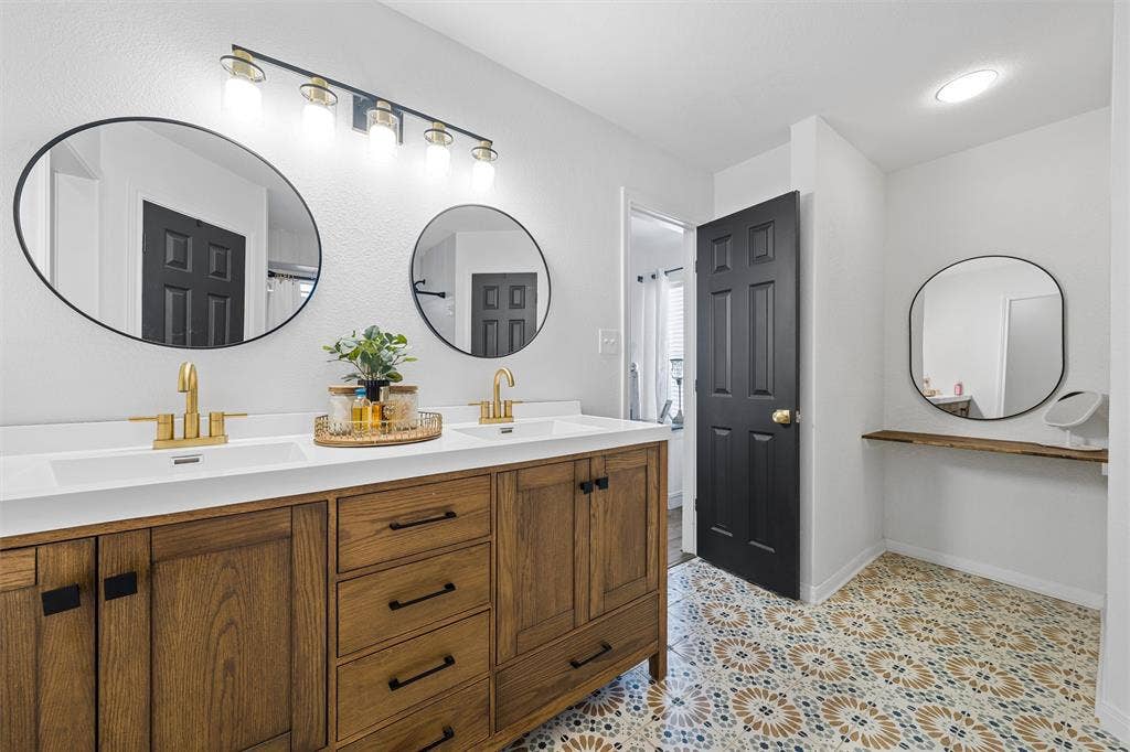 Dual vanity with white countertop, brass fixtures, and wood-finish cabinetry