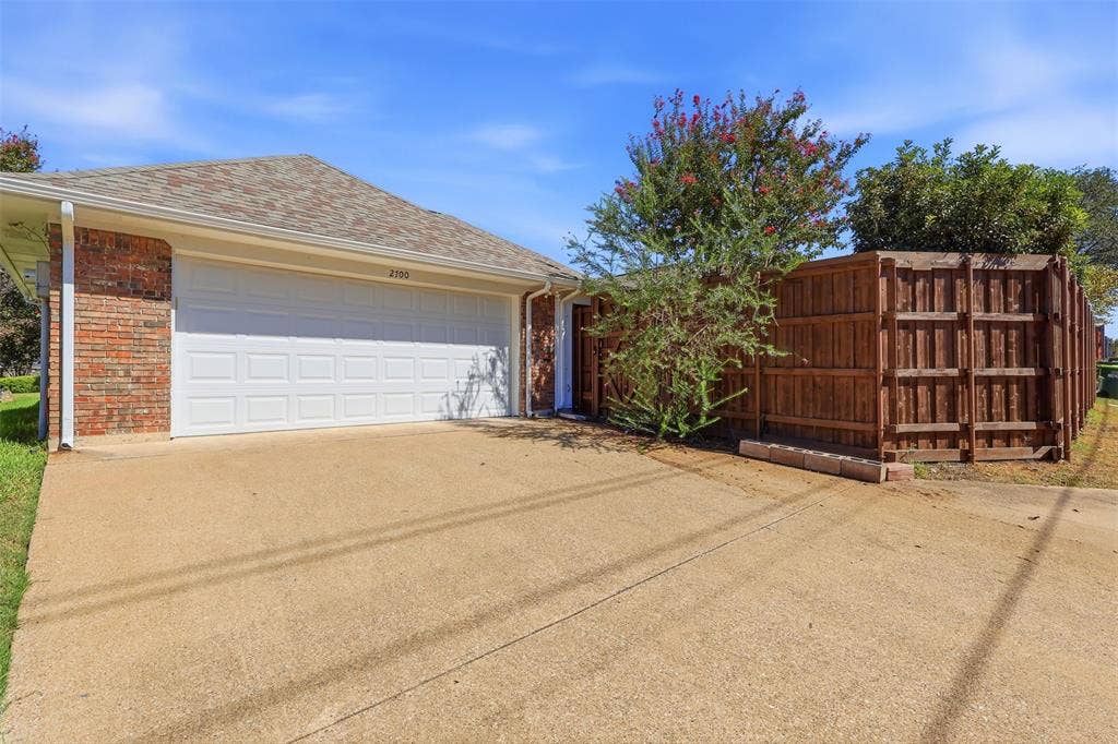 2700 Nighthawk Drive, Plano, TX 75025 Brick exterior with an attached two-car garage, concrete driveway, and wood privacy fencing