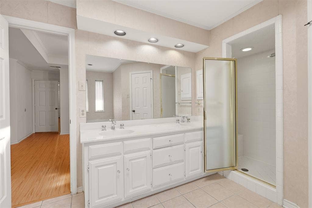 2700 Nighthawk Drive, Plano, TX 75025 Dual vanity with integrated sinks, recessed lighting, expansive wall mirror, and an enclosed shower with a folding glass door