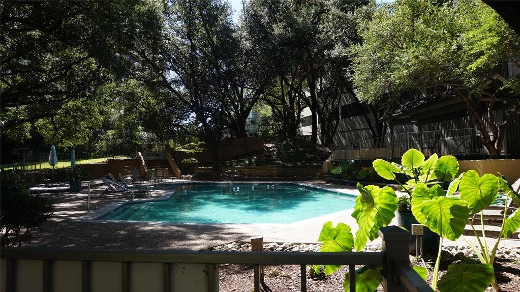 3883 Turtle Creek Boulevard, #1114, Dallas, TX 75219 Swimming pool with a pebble aggregate deck, surrounded by mature trees and landscaping