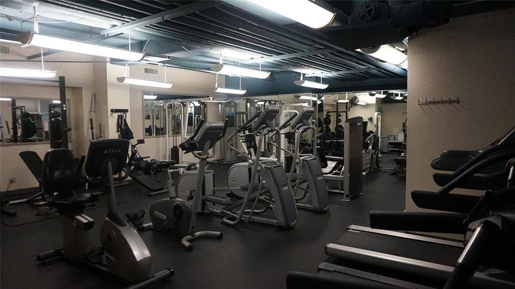 3883 Turtle Creek Boulevard, #1114, Dallas, TX 75219 Fitness facility with a rubberized floor, mirrored wall, exposed ceiling, and fluorescent lighting