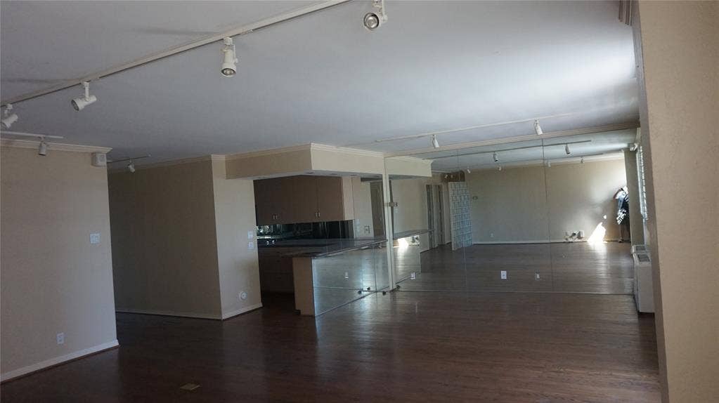 3883 Turtle Creek Boulevard, #1114, Dallas, TX 75219 Open-concept living area with dark wood-finish flooring, track lighting, and a mirrored wall