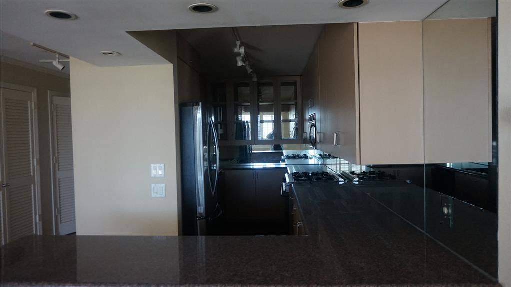 3883 Turtle Creek Boulevard, #1114, Dallas, TX 75219 Kitchen featuring light-toned cabinetry, a built-in oven, gas cooktop, and dark stone-finish countertops