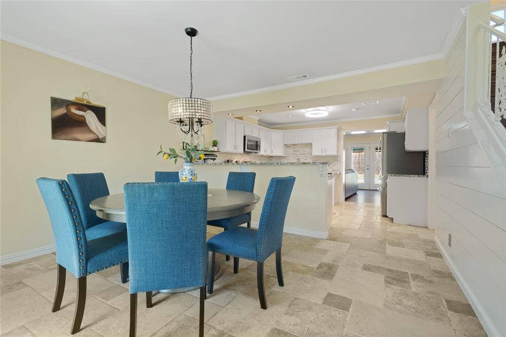 Recessed lighting and a decorative chandelier illuminate the dining area