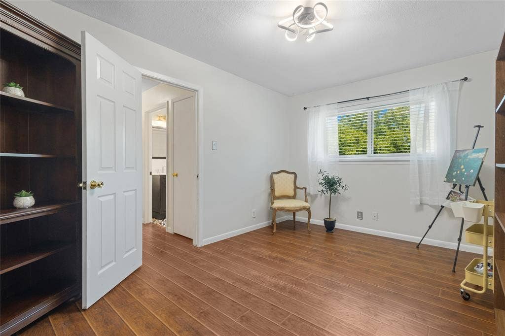 Wood-finish flooring throughout, bright white walls, modern ceiling light fixture, built-in shelving, and a window with natural light