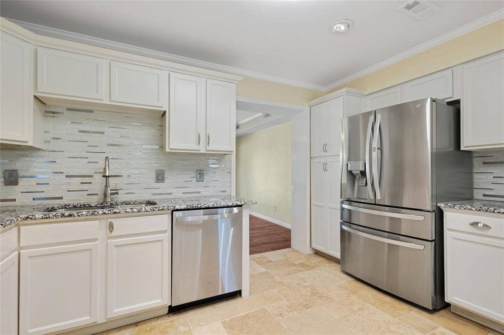 Kitchen with white shaker-style cabinetry, stainless steel appliances, speckled stone countertops, and a mosaic tile backsplash
