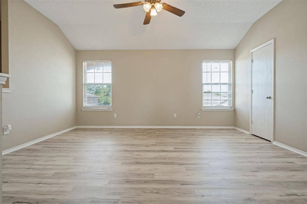 1308 Arbordale Court, Lancaster, TX 75134 Vaulted ceiling with a ceiling fan, two windows, wood-finish flooring, and light-colored walls