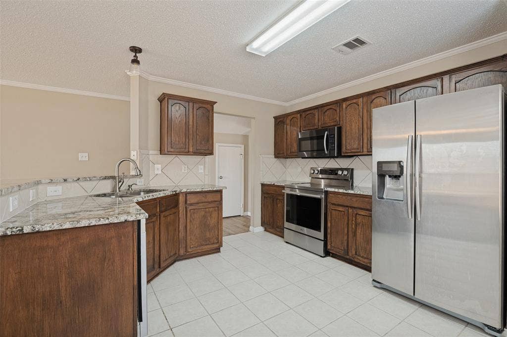 1308 Arbordale Court, Lancaster, TX 75134 Kitchen featuring wood cabinetry, white tile flooring, stainless steel appliances, and light-toned countertops