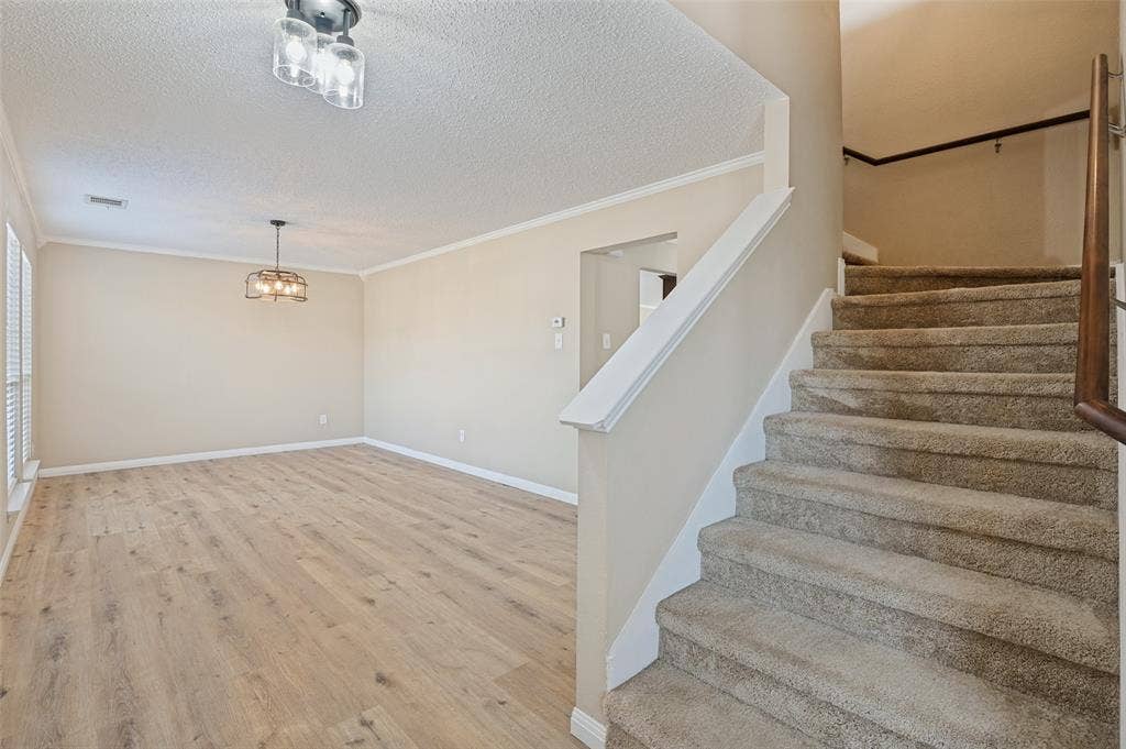 1308 Arbordale Court, Lancaster, TX 75134 Wood-finish flooring, staircase with carpeted treads, decorative light fixture, crown molding, and a traditional handrail