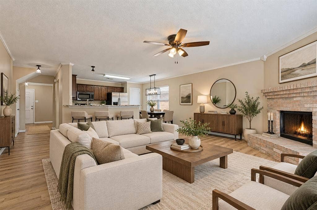 1308 Arbordale Court, Lancaster, TX 75134 Open-concept living area with wood-finish flooring, a brick fireplace, and a ceiling fan