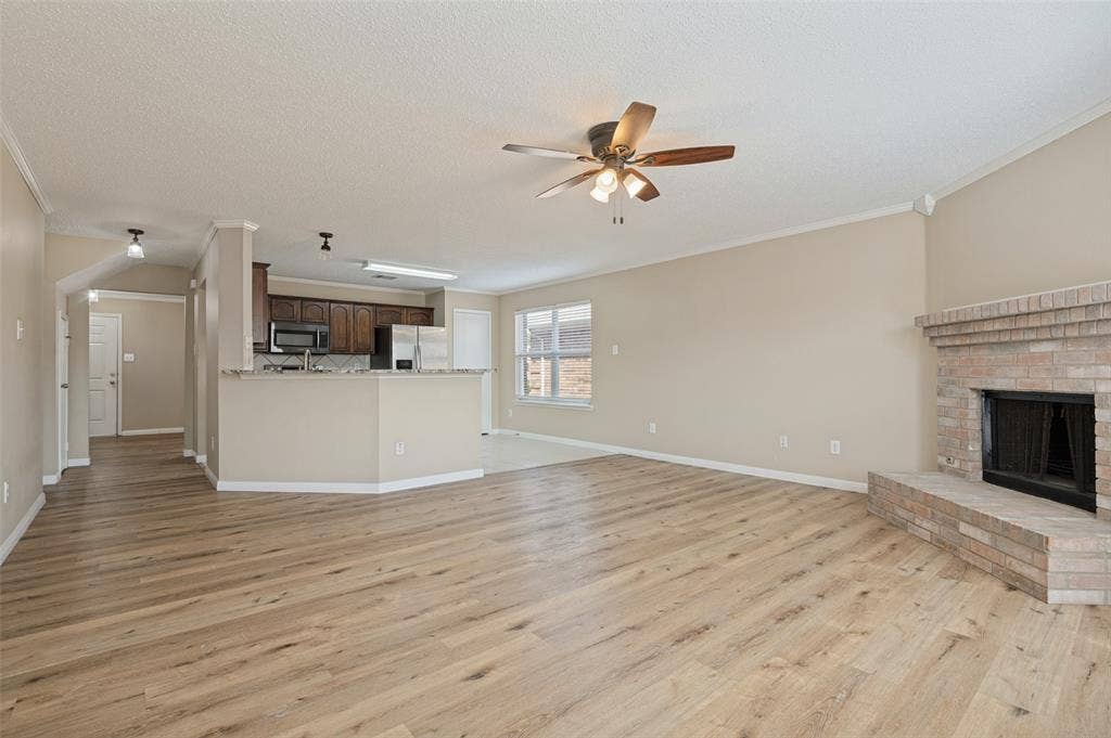 1308 Arbordale Court, Lancaster, TX 75134 Spacious living area featuring wood-finish flooring, a brick fireplace with hearth, and a ceiling fan