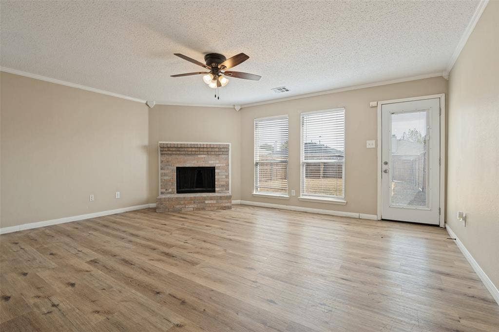 1308 Arbordale Court, Lancaster, TX 75134 Living area featuring wood-finish flooring, a brick-surround fireplace, a ceiling fan, and multiple windows with blinds