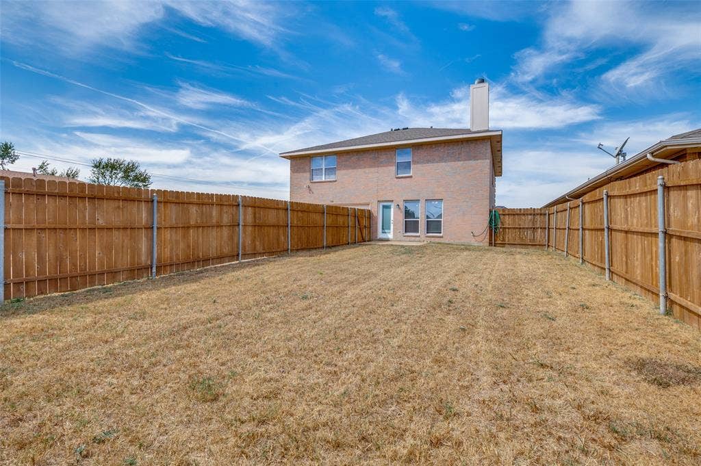 1308 Arbordale Court, Lancaster, TX 75134 Expansive fenced backyard with brick exterior, multiple windows, and a prominent chimney