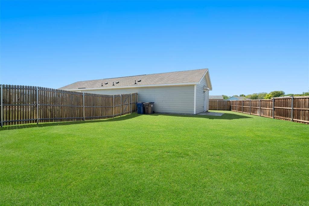 250 Herman Lane, Princeton, TX 75407 Expansive green lawn, wood privacy fencing, light-colored siding, and a gabled roofline