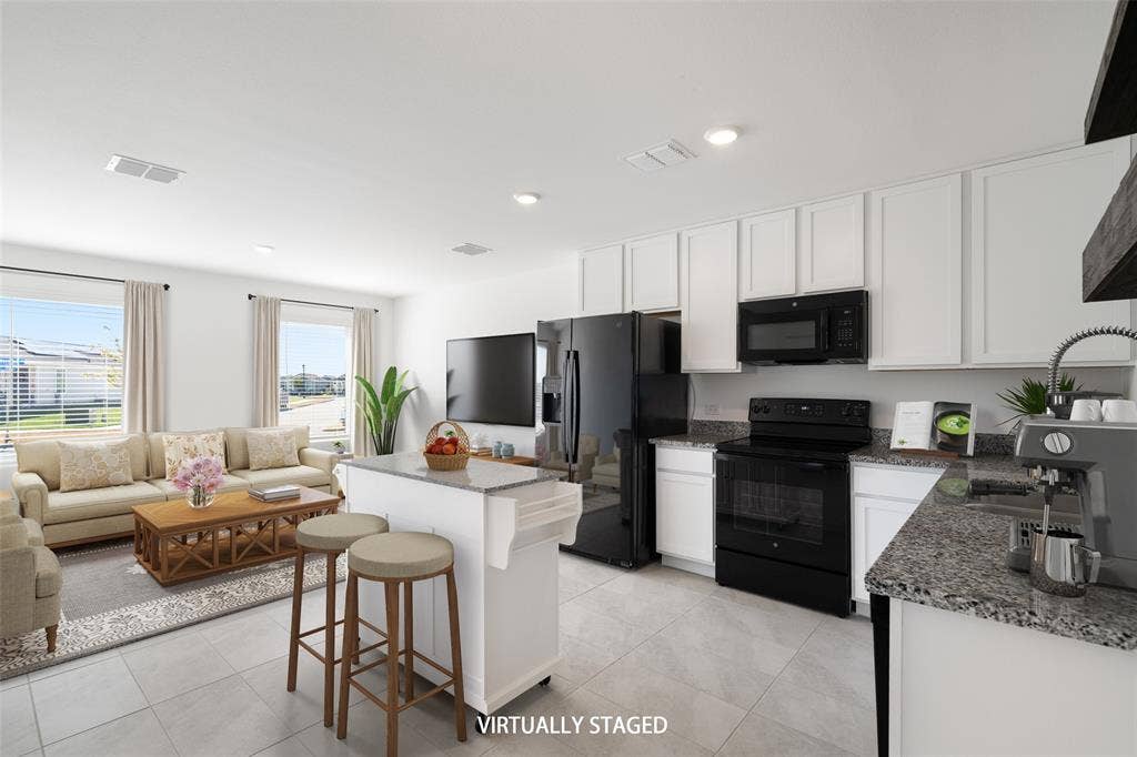 250 Herman Lane, Princeton, TX 75407 Open concept living space featuring a kitchen island with seating, granite-finish countertops, black appliances, white shaker-style cabinetry, and tile flooring