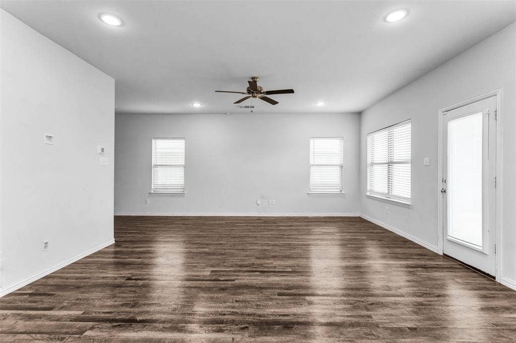 Wood-finish flooring, recessed lighting, ceiling fan, multiple windows, and a glass-paneled door