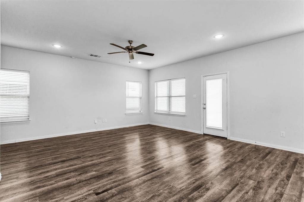 Spacious room featuring wood-finish flooring, multiple windows with blinds, a ceiling fan, and recessed lighting