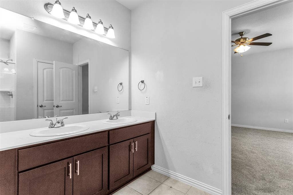 Dual vanity with white undermount sinks, wall-mounted lighting, and dark wood-finish cabinetry