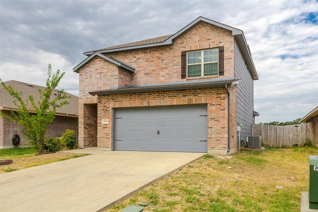 Brick exterior with gray siding accents, attached garage, concrete driveway, and covered entry