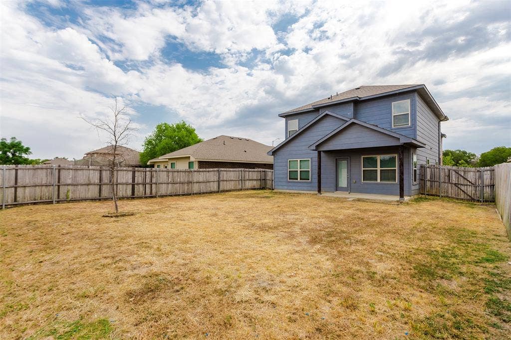 Two-story residence with a covered patio, enclosed by a wood privacy fence