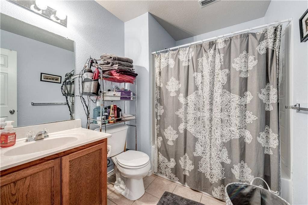 12829 Pricklybranch Drive, Fort Worth, TX 76244 Wood-finish vanity with an integrated sink, polished chrome faucet, and overhead bar lighting