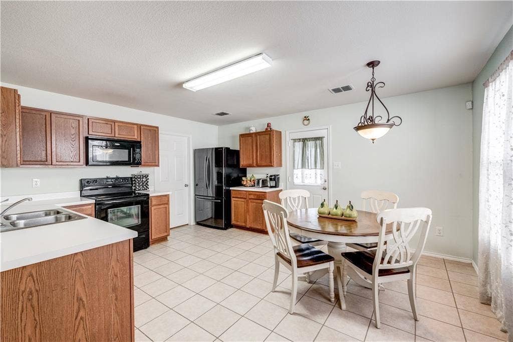 12829 Pricklybranch Drive, Fort Worth, TX 76244 Kitchen featuring wood-finish cabinetry, black appliances, white countertops, and tile flooring