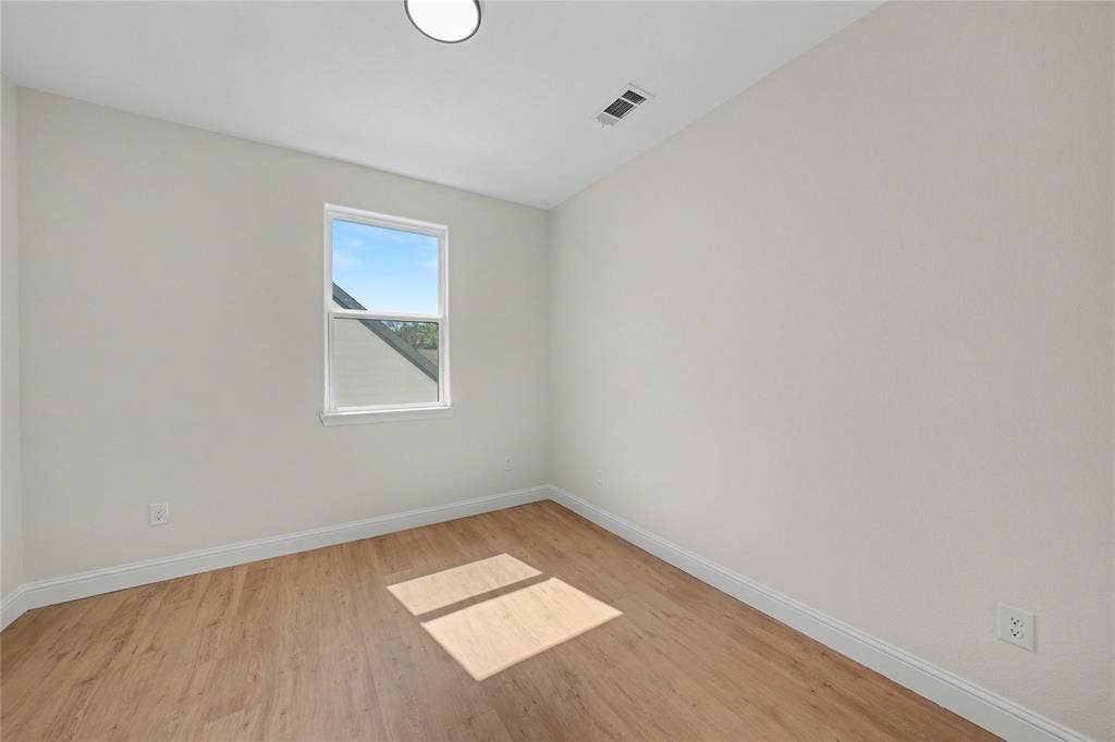 817 Stamps Avenue, Fort Worth, TX 76114 Upstairs bedroom featuring wood-finish flooring, white walls, and a single window with a white frame