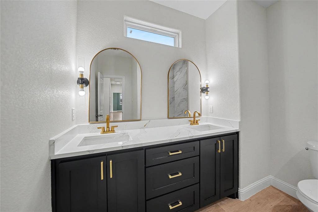817 Stamps Avenue, Fort Worth, TX 76114 Double vanity with black cabinetry, gold-finish hardware, and a white countertop