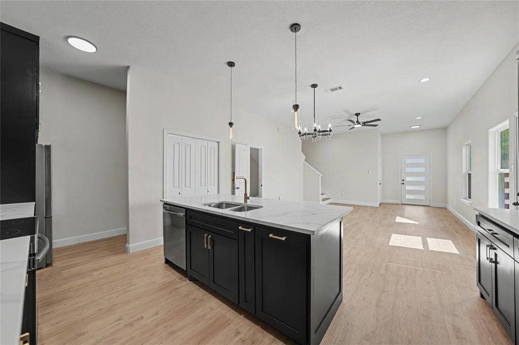 817 Stamps Avenue, Fort Worth, TX 76114 Open-concept living space featuring wood-finish flooring, a kitchen island with stone countertops, a stainless steel dishwasher, and a contemporary chandelier