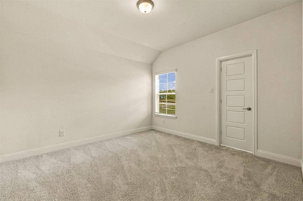 Neutral interior space featuring high ceilings, wall-to-wall carpeting, a single-hung window, and a five-panel interior door