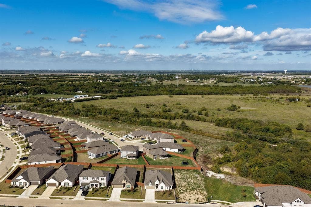 Aerial perspective of residential properties featuring concrete driveways, asphalt shingle roofs, and fenced rear perimeters